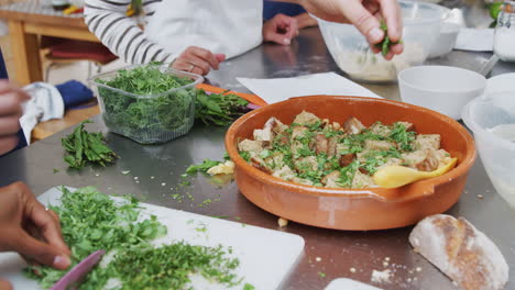 Close-Up-Of-Woman-Chopping-And-Adding-Fresh-Herbs-To-Dish-In-Kitchen-Cookery-Class