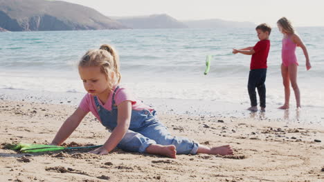 Children-Having-Fun-On-Beach-Digging-In-Sand-And-Exploring-With-Fishing-Net