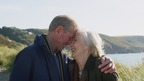 Loving-Active-Senior-Couple-Hugging-As-They-Walk-Along-Coastal-Path-Together