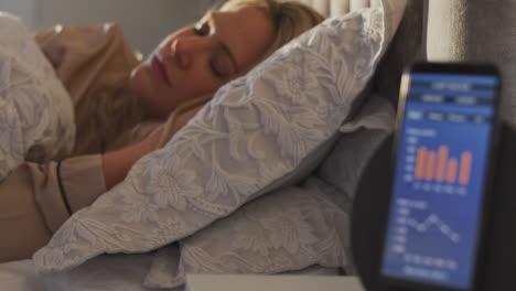Woman-Sleeping-In-Bed-With-Sleep-Data-App-Running-On-Mobile-Phone-On-Bedside