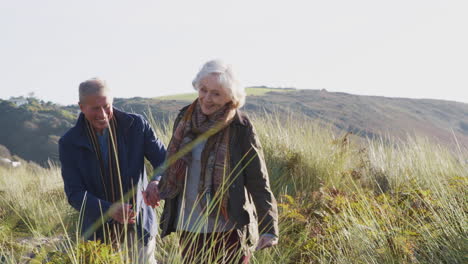 Loving-Active-Senior-Couple-Walking-Hand-In-Hand-Through-Countryside-Together