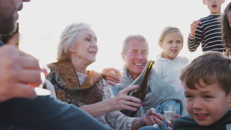 Familia-Multigeneracional-Relajándose-Con-Bebidas-En-Vacaciones-De-Invierno-En-La-Playa