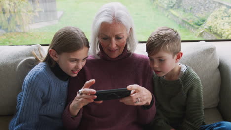 Großmutter-Spielt-Zu-Hause-Videospiel-Mit-Enkelkindern-Auf-Dem-Handy
