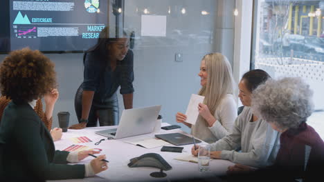 Blick-Durch-Das-Glas-Auf-Geschäftsfrauen,-Die-Bei-Kreativen-Treffen-Am-Tisch-Im-Modernen-Büro-Zusammenarbeiten