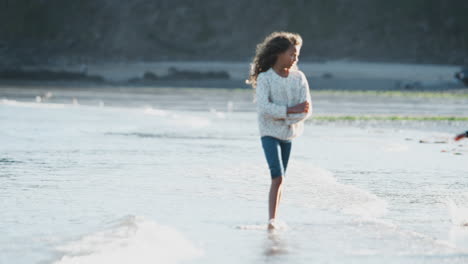 Boy-And-Girl-Playing-And-Jumping-Over-Waves-On-Autumn-Beach-Vacation