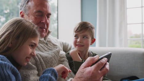 Großvater-Spielt-Zu-Hause-Videospiel-Mit-Enkelkindern-Auf-Dem-Handy