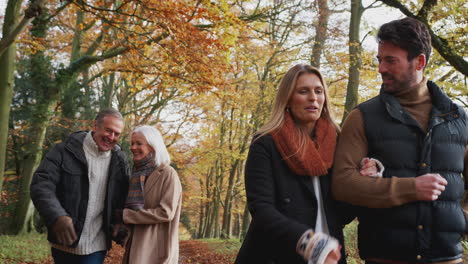 Senior-Couple-Walking-Along-Path-Through-Autumn-Countryside-With-Adult-Offspring