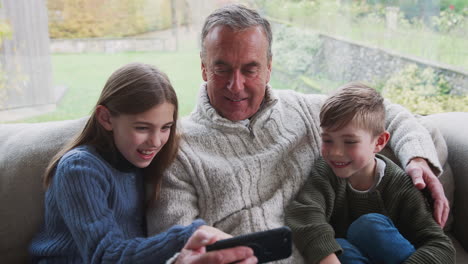 Großvater-Spielt-Zu-Hause-Videospiel-Mit-Enkelkindern-Auf-Dem-Handy