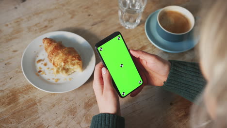 Close-Up-Of-Woman-Looking-At-Green-Screen-With-Copy-Space-On-Mobile-Phone-In-Cafe