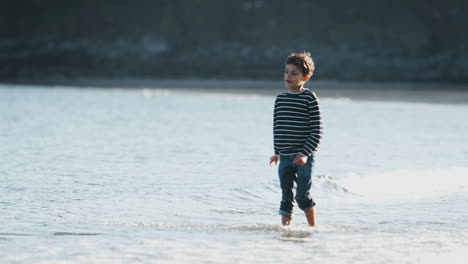 Boy-Playing-And-Jumping-Over-Waves-On-Autumn-Beach-Vacation