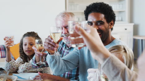 Mehrgenerationenfamilie-Stößt-Mit-Wein-An,-Während-Sie-Sich-Zu-Hause-Zum-Essen-Trifft