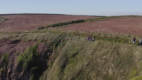 Drone-Shot-Of-Group-Of-Friends-Taking-Selfie-As-They-Hike-Along-Cliffs-On-Coastal-Path