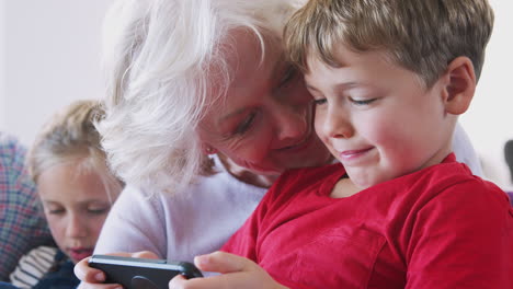 Großmutter-Spielt-Zu-Hause-Videospiel-Mit-Enkel-Auf-Dem-Handy