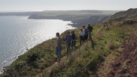 Drone-Shot-Of-Group-Of-Friends-Hiking-Along-Cliffs-On-Coastal-Path