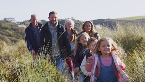 Multi-Generation-Family-Walking-Along-Path-Through-Hills-In-Countryside-Together