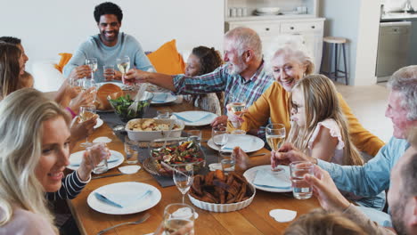 Familia-Multigeneracional-Brindando-Con-Vino-Mientras-Se-Reúnen-Para-Comer-En-Casa