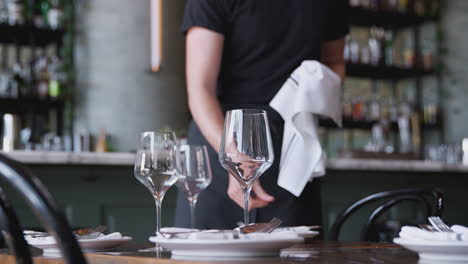 Close-Up-Of-Male-Waiter-Polishing-Cutlery-On-Table-Before-Service-In-Bar-Restaurant