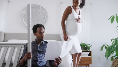 Una-Pareja-Afroamericana-Con-Una-Mujer-Embarazada-Mira-Las-Instrucciones-Para-Construir-Una-Cuna-De-Autoensamblaje