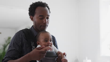 Father-Playing-Game-With-Smiling-Baby-Son-In-Sling-At-Home