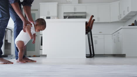 Close-Up-Of-Father-Encouraging-Smiling-Baby-Son-To-Take-First-Steps-And-Walk-At-Home