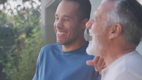 Senior-Hispanic-Man-Talking-And-Laughing-With-Adult-Son-In-Garden-At-Home