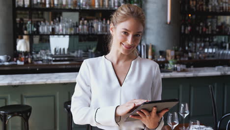 Retrato-De-Una-Mujer-Propietaria-Del-Bar-Restaurante-Parada-En-El-Mostrador-Usando-Una-Tableta-Digital