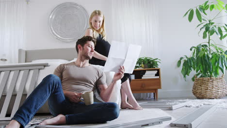 Young-Couple-With-Pregnant-Woman-In-Bedroom-Look-At-Instructions-For-Self-Assembly-Baby-Cot