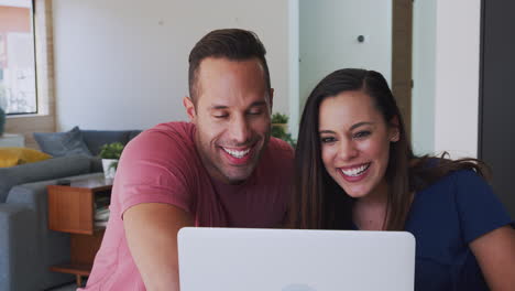 Hispanic-Couple-At-Home-With-Laptop-Having-Video-Chat-With-Family