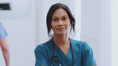 Portrait-Of-Female-Doctor-With-Stethoscope-Wearing-Scrubs-In-Busy-Hospital-Corridor