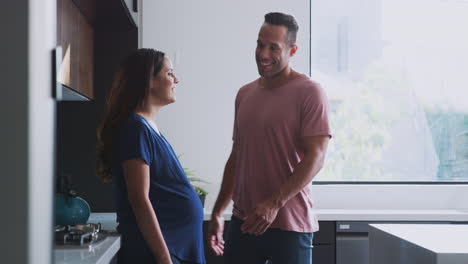 Loving-Hispanic-Husband-With-Pregnant-Wife-At-Home-In-Kitchen-Together