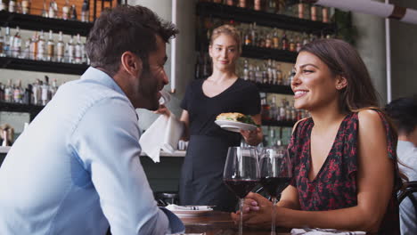 Kellnerin-Serviert-Essen-Für-Ein-Romantisches-Paar,-Das-Am-Tisch-Im-Restaurant-Sitzt