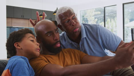 Multi-Generation-Male-African-American-Family-Sitting-On-Sofa-At-Home-Posing-For-Selfie
