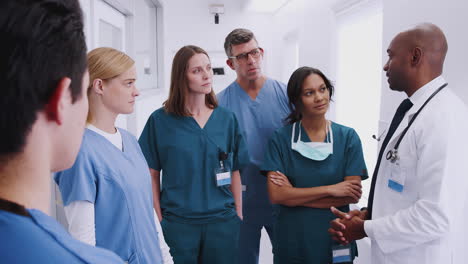 Multi-Cultural-Medical-Team-Having-Meeting-In-Hospital-Corridor