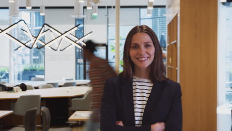 Businesswoman-Standing-In-Busy-Modern-Office--With-Time-Lapse-Of-Busy-Colleagues-In-Background