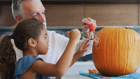 Grandfather-And-Granddaughter-Carving-Halloween-Lantern-From-Pumpkin-At-Home
