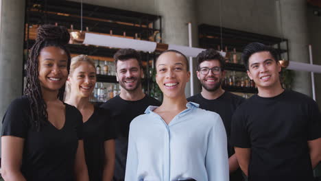 Portrait-Of-Smiling-Female-Owner-Of-Restaurant-Bar-With-Team-Of-Waiting-Staff-Standing-By-Counter
