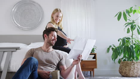 Young-Couple-With-Pregnant-Woman-In-Bedroom-Look-At-Instructions-For-Self-Assembly-Baby-Cot