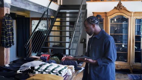 Male-Owner-Of-Fashion-Store-Using-Digital-Tablet-To-Check-Stock-In-Clothing-Store