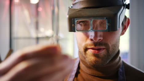 Close-Up-Of-Male-Jeweller-Looking-At-Ring-Through-Headband-Magnifiers-In-Studio