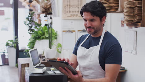 Portrait-Of-Male-Owner-With-Digital-Tablet-Standing-Behind-Sales-Desk-Of-Florists-Store