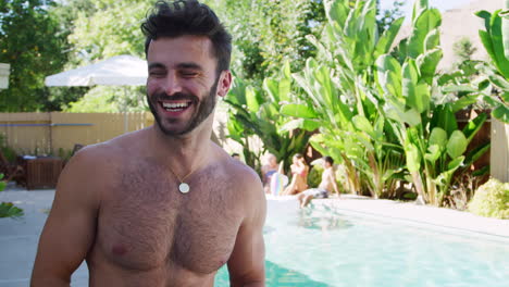 Portrait-Of-Smiling-Bare-Chested-Hispanic-Man-Outdoors-With-Friends-Enjoying-Summer-Pool-Party