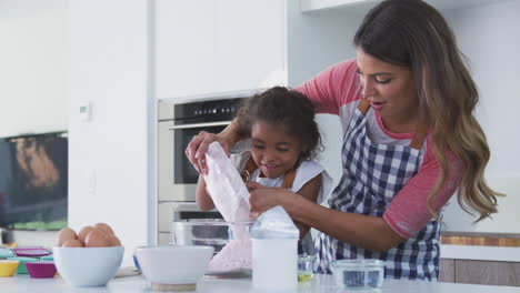Hispanic-Mother-And-Daughter-Having-Fun-In-Kitchen-Baking-Cake-Together