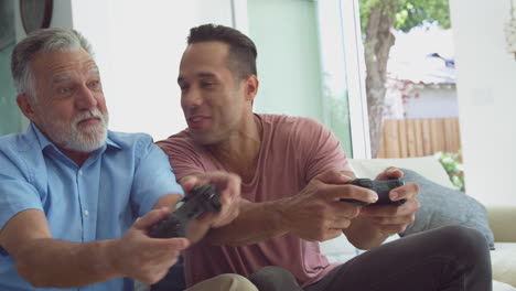 Hispanischer-Vater-Und-Erwachsener-Sohn-Sitzen-Zu-Hause-Auf-Dem-Sofa-Und-Spielen-Gemeinsam-Videospiele