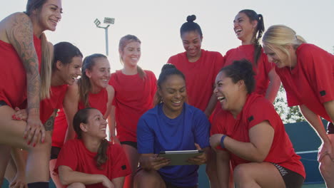 Entrenadora-Discutiendo-Tácticas-Con-El-Equipo-De-Fútbol-Femenino-Usando-Una-Tableta-Digital-Antes-Del-Partido