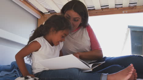 Hispanische-Mutter-Und-Tochter-Sitzen-Zu-Hause-Auf-Dem-Etagenbett-Der-Mädchen-Und-Lesen-Gemeinsam-Ein-Buch