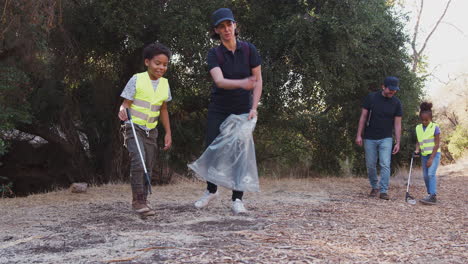 Erwachsene-Teamleiter-Mit-Einer-Gruppe-Von-Kindern-Im-Outdoor-Aktivitätscamp,-Die-Gemeinsam-Müll-Sammeln