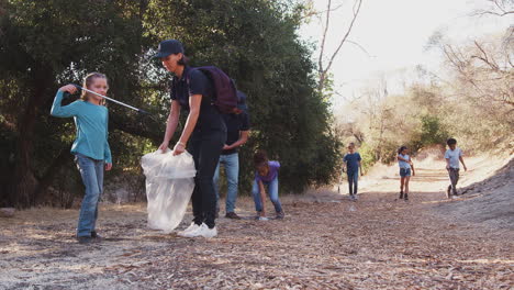 Adult-Team-Leaders-With-Group-Of-Children-At-Outdoor-Activity-Camp-Collecting-Litter-Together