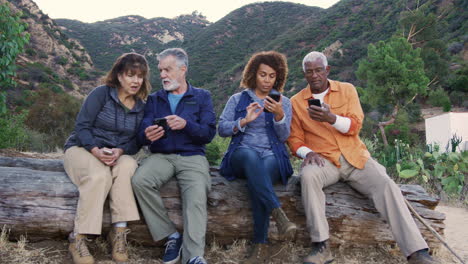 Gruppe-älterer-Freunde-Auf-Einer-Wanderung-Auf-Dem-Land,-Die-Mobiltelefone-überprüft,-Aus-Angst,-Etwas-Zu-Verpassen