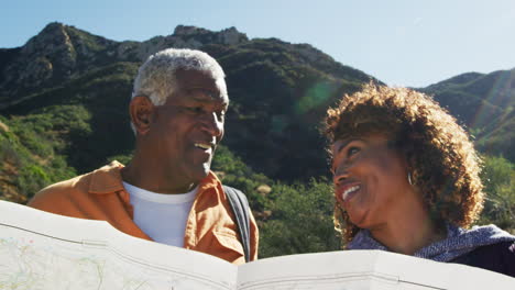 Älteres-Afroamerikanisches-Paar-Blickt-Auf-Die-Karte,-Während-Sie-Gemeinsam-Den-Weg-In-Der-Landschaft-Entlang-Wandern