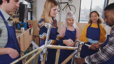 Multi-Cultural-Team-Of-Trainees-In-Workshop-Learn-How-To-Assemble-Hand-Built-Bicycle-Frame-Together